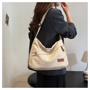 Vue rapprochée d'un modèle portant un sac à bandoulière minimaliste en toile crème et cuir.
