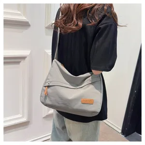 Mannequin portant un sac bandoulière minimaliste en toile grise dans un cadre décontracté