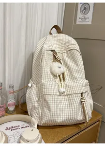 Detail shot of a Japanese-style plaid backpack with a cute pom-pom charm.