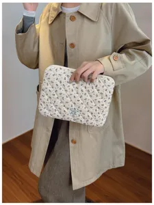 Detailed view of the quilted floral laptop sleeve held by a model in a trench coat
