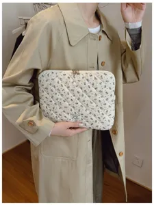 Floral quilted laptop sleeve bag held by a model in a classic beige trench coat