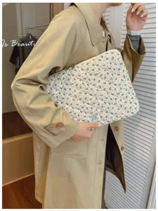Detailed view of a stylish floral quilted laptop sleeve held by a woman in a beige coat
