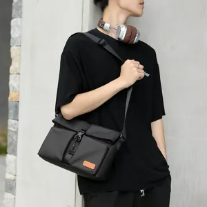 Stylish man wearing a black matte messenger bag with orange patch detail for street fashion.