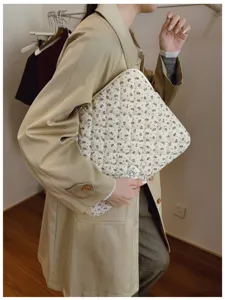 Stylish floral quilted laptop sleeve bag held by a woman in a fashion lifestyle setting