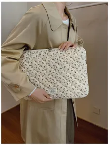 Detailed view of floral quilted laptop sleeve held by a person in a trench coat