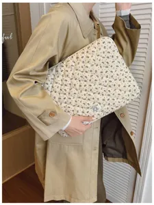 Stylish quilted floral laptop sleeve being held by a model in a beige trench coat.