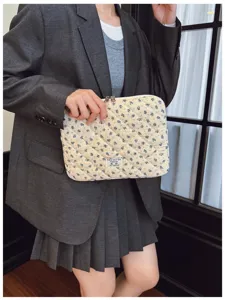 Lifestyle detail of a floral quilted laptop sleeve with blue flower patterns held by a model
