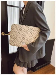 Lifestyle shot of a stylish quilted floral laptop sleeve held by a model in a grey blazer.