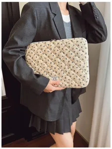 Detail view of a vintage quilted floral laptop sleeve with a small minimalist fabric label.