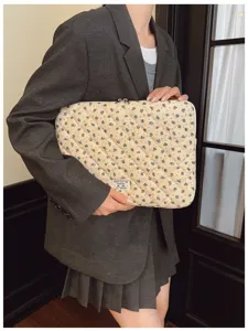 Detailed view of the stylish quilted floral laptop sleeve held by a model in a blazer