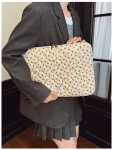 Floral quilted laptop sleeve bag held by a model in a gray blazer style