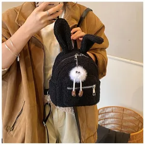 Vista detallada de una linda mochila de felpa negra con orejas de conejo y colgante peludo