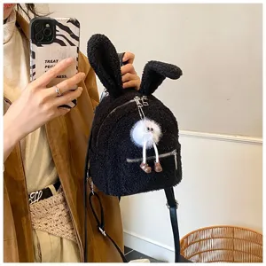 Primer plano de una mochila de peluche negra con orejas de conejo y amuleto suave