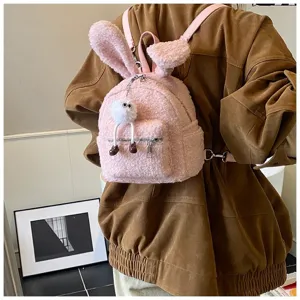 Primer plano de mochila de peluche rosa con orejas de conejo y llavero de pompón blanco