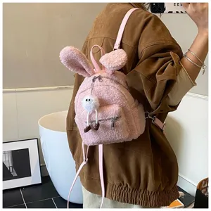 Detalle de una linda mochila de felpa rosa con orejas de conejo y una chaqueta marrón.