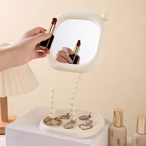 Minimalist beige rotating desktop vanity mirror with a functional jewelry storage tray base