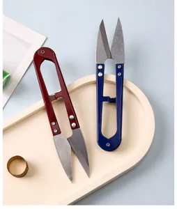 Macro detail of red and blue U-shaped high-carbon steel thread snips on a tray.