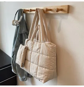 Gedetailleerd zicht op beige gewatteerde draagtas aan een houten rek met lifestyle-items