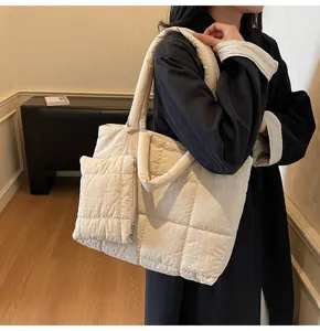 Gedetailleerd overzicht van de grote beige gewatteerde puffer tas gedragen door een model.