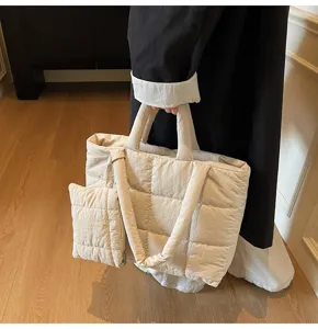 Detailopname van een crèmekleurige minimalistische gewatteerde puffer tas met klein tasje