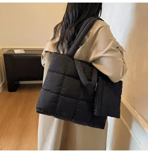 Gedetailleerd zicht op een stijlvolle zwarte gewatteerde puffer tas gedragen door een vrouw.