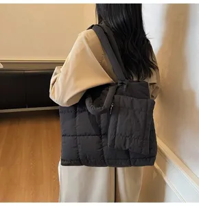 Model met een zwarte gewatteerde puffer-tas met bijpassend zakje in een detailweergave.