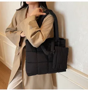 Detailoverzicht van een zwarte gewatteerde shopper gecombineerd met een beige trenchcoat