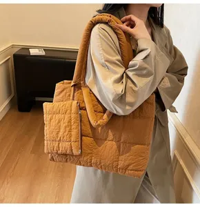 Dichtbij van een bruine gewatteerde puffer tote tas met bijpassend etui gedragen door model