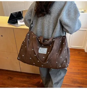 Detail shot of the brown quilted travel duffel bag featuring cute bow prints and durable straps.