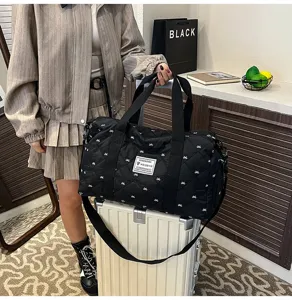 Black quilted travel duffel bag with shoulder strap and top handles for gym or short trips.