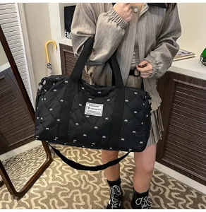 Detailed view of the black quilted travel duffle bag with cute bows, showing durable handles.