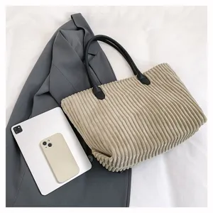 Detailopname van een modieuze beige corduroy draagtas met een stijlvolle grijze blazer.