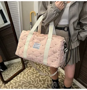 Pink quilted travel duffel bag with white handles, stylish casual gym shoulder bag.