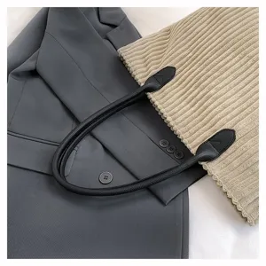Detailopname van corduroy draagtas met zwarte leren handvatten en textuur
