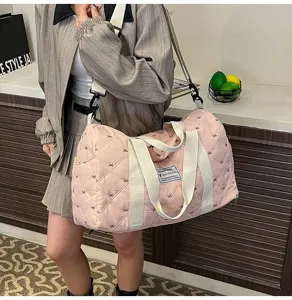 Pink quilted travel duffel bag with white straps, lightweight fashion casual handbag.