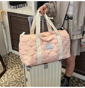 Pink quilted travel duffel bag with bow embroidery, lightweight portable luggage bag.