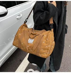 Detailed shot of a stylish quilted travel duffel bag with bow pattern and sturdy canvas straps.