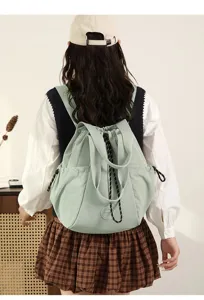 Back view of a model wearing a light green lightweight nylon drawstring tote bag backpack.
