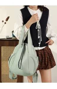 Detailed view of the mint green nylon shoulder bag held by a model in a casual outfit.