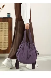 Model holding a purple lightweight nylon tote bag with drawstring closure in a casual setting.