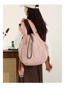 Model carrying a lightweight pink nylon tote bag in a stylish lifestyle indoor setting
