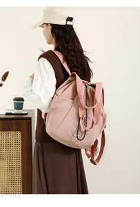 Detail of a light pink nylon drawstring backpack worn by a model in spring style.