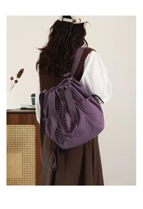 Back view of a stylish woman carrying a purple nylon drawstring bag in a cozy room