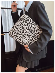 Leopard print laptop sleeve held by a model in a stylish grey suit jacket