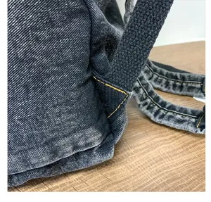 Detail view of the durable denim fabric and contrast stitching of the woman backpack