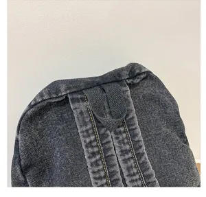 Detailed macro close-up of the durable top handle and stitching on a grey denim backpack
