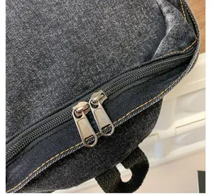 Close-up of the smooth dual metal zippers on this stylish black washed denim backpack