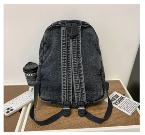 Close-up showing the adjustable back straps of a vintage washed black denim backpack.