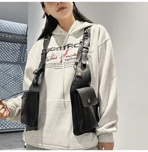 Detail view of a black tactical vest bag worn over a grey hoodie for a streetwear look.