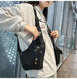 Detailed shot of a black tactical vest bag with bronze snaps worn over a light gray hoodie